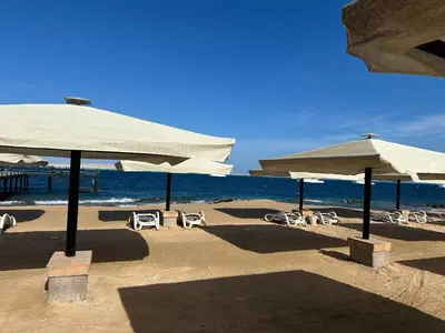 a beach with chairs and umbrellas and the ocean at The view -Nubian One bedroom in Hurghada