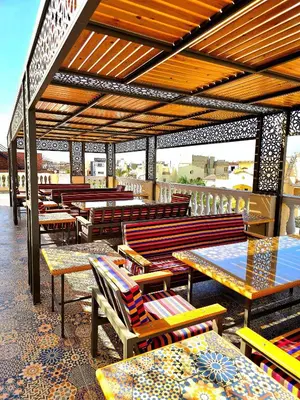 a patio with wooden tables and chairs and benches at Elnahla Villa in Hurghada