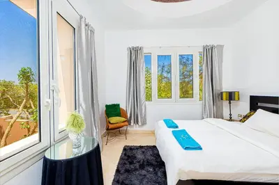 a white bedroom with a bed and a glass table at Townhouse with roof terrace,balcony and large pool in Hurghada