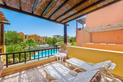 a patio with a couch and a table on a balcony at Townhouse with roof terrace,balcony and large pool in Hurghada