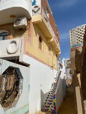 a building with a staircase on the side of it at Maleka nubian guest house in Jazīrat Suhayl