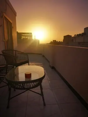 a sunset on a balcony with a table and chairs at I&A studia in Hurghada