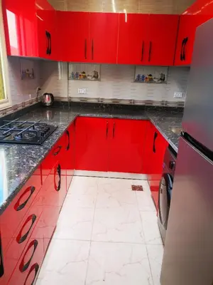 a kitchen with red cabinets and a white tile floor at I&A studia in Hurghada