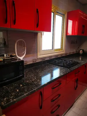 a kitchen with red cabinets and a black counter top at I&A studia in Hurghada