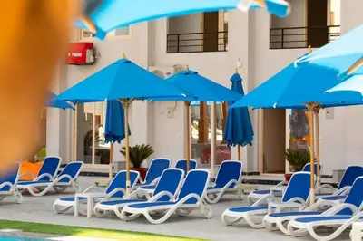 a group of blue chairs and umbrellas next to a pool at Sami and Sam studio apartment in Hurghada
