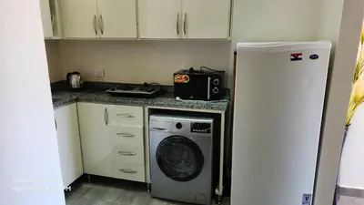 a kitchen with a refrigerator and a washing machine at Chalet - Mirage Bay Resort & Aqua Park in Hurghada