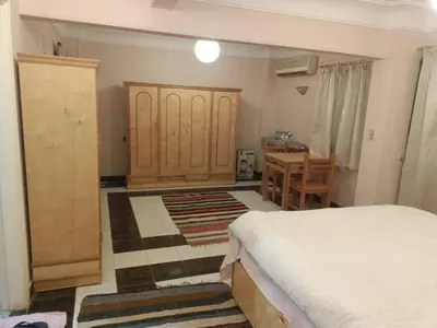 a bedroom with a bed and a wooden cabinet and a desk at fayrouz apartment in Jazīrat al ‘Awwāmīyah