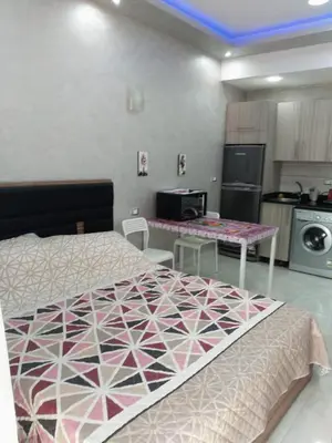 a bedroom with a bed and a kitchen with tables at Compound El makramia 504 in Hurghada