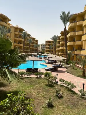 a swimming pool with tables and umbrellas in a resort at Stefy Holiday Hurghada in Hurghada