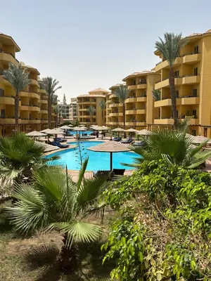 a resort swimming pool with palm trees and buildings at Stefy Holiday Hurghada in Hurghada