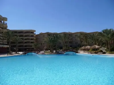 a large swimming pool with palm trees and buildings at Palma Resort Hurghada in Hurghada