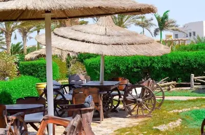 a table and chairs under a straw umbrella at Palma Resort Hurghada in Hurghada