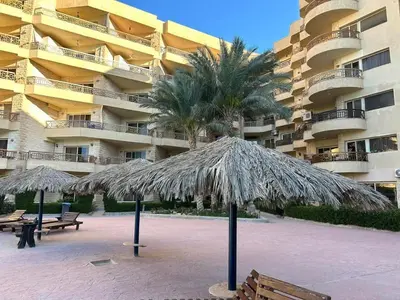two straw umbrellas in front of a large building at Palma Resort Hurghada in Hurghada