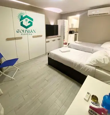 a hotel room with two beds and a television at Cozy studio in Bali in Hurghada