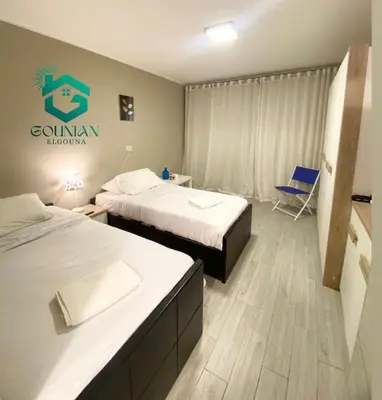 a hotel room with two beds and a chair at Cozy studio in Bali in Hurghada