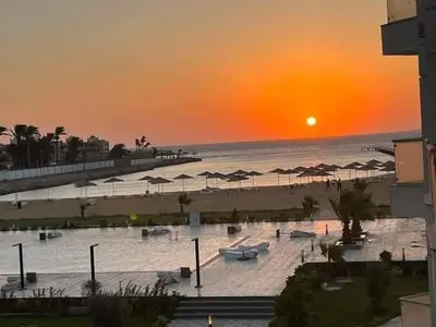 a beach with umbrellas and the ocean at sunset at سكانديك ريزورت in Hurghada