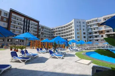 a group of chairs and blue umbrellas next to a pool at Sam and Sami studio apartment in Hurghada