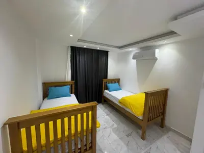 two beds in a small room with yellow and blue pillows at Fanadir L406 in Hurghada