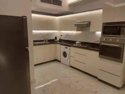 a kitchen with white cabinets and a washer and dryer at Fanadir L406 in Hurghada