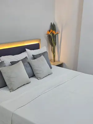 a white bed with pillows and a vase with a flower at Marina Views Hurghada in Hurghada