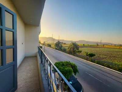 a balcony with a view of a road and palm trees at Casablanca guest house᭄ꦿ in Luxor