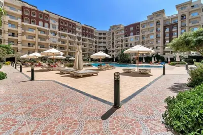a courtyard with tables and umbrellas and a pool at Private Garden Studio Wi-Fi and Beach Access in Hurghada