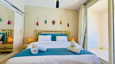 a bedroom with a large bed with blue sheets at Cozy apartment in Mangroovy in Hurghada