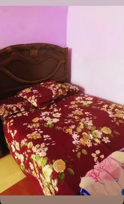 a bed with a red comforter with flowers on it at Nubian night in Jazīrat Suhayl