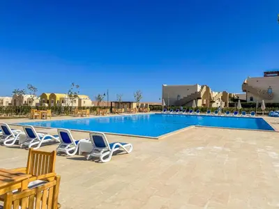 a swimming pool with lounge chairs in a resort at 2 bed rooms apartment in makadi heights in Hurghada