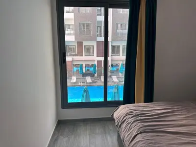 a bedroom with a view of a swimming pool through a window at Imperial resort Hurghada, 1 bedroom luxury resort in Hurghada