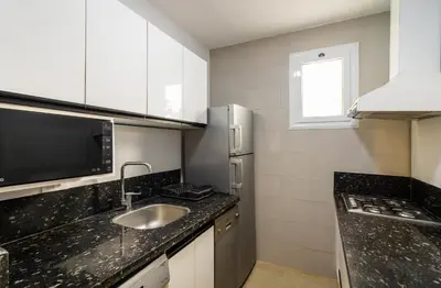 a small kitchen with a sink and a microwave at Al Saraya Sahl Hasheesh by Peaks One Bedroom Apartment With Pool View C101 in Hurghada