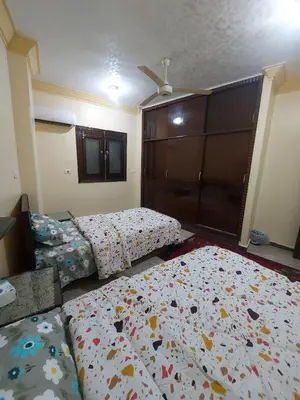 a bedroom with two beds and a bedspread with flowers at Entire hotel apartment overlooking the Nile in Aswan