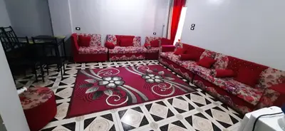 a living room with a red couch and a rug at Downtown Apartment in Aswan