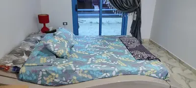 a bed with a blue comforter and a window at اويسيس مارينا in Hurghada
