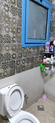 a bathroom with a white toilet and a blue window at اويسيس مارينا in Hurghada