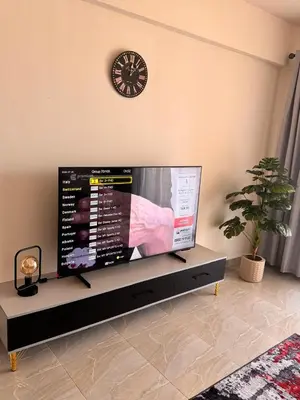 a large flat screen tv in a living room with a clock at Apartment in Port Ghalib Marina City in Port Ghalib