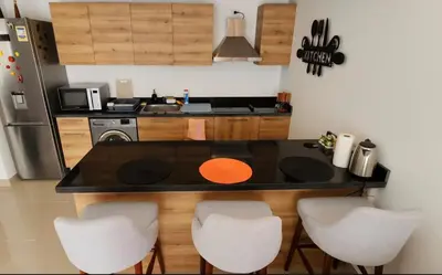 a kitchen with a black counter top and white chairs at Modern ground one bedroom apt G cribs in El Gouna