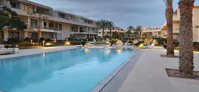 a large swimming pool with palm trees and buildings at Modern ground one bedroom apt G cribs in El Gouna