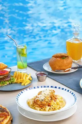 a table with plates of pasta and bread and a drink at Arena Beach Resort - Premium Suites in Hurghada