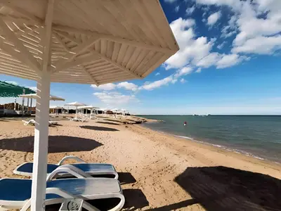 a beach with chairs and umbrellas and the ocean at Arena Beach Resort - Premium Suites in Hurghada