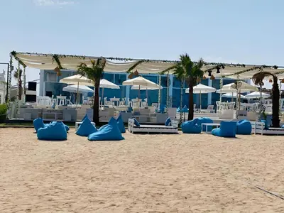 a beach with blue and white chairs and umbrellas at Arena Beach Resort - Premium Suites in Hurghada