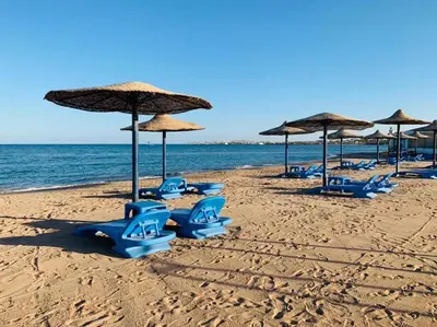 a group of blue chairs and umbrellas on a beach at Sea View Apartment Cecelia Resort in Hurghada