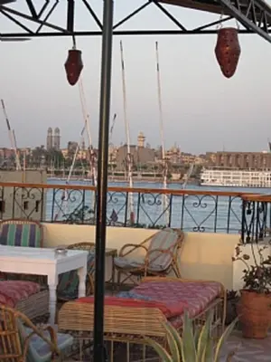 a balcony with chairs and a table and a ship at Memnon Apartments in Luxor