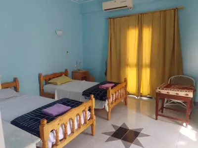 a bedroom with two beds and a chair in it at Memnon Apartments in Luxor