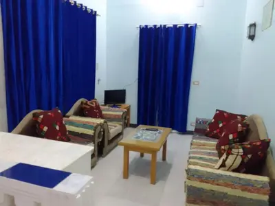 a living room with blue curtains and couches and a table at Memnon Apartments in Luxor