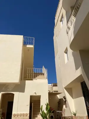 an alley between two buildings with a blue sky at Memnon Apartments in Luxor