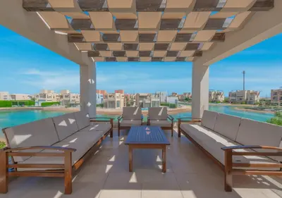 a patio with benches and a table and a pool at Beautiful 4BR Villa in Tawila El Gouna Private Pool & Lagoon Access in Hurghada