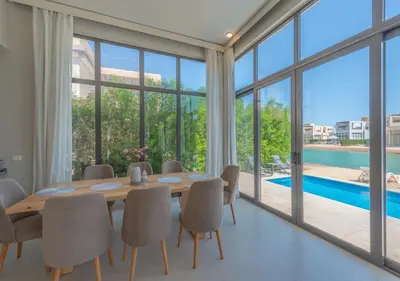 a dining room with a table and chairs and a pool at Beautiful 4BR Villa in Tawila El Gouna Private Pool & Lagoon Access in Hurghada