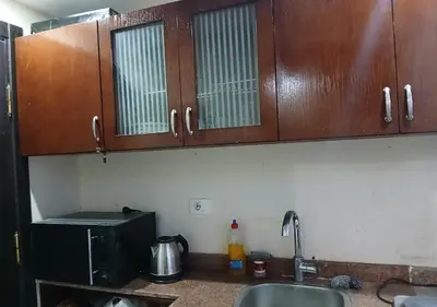 a kitchen with wooden cabinets and a sink and a microwave at Luxury Cecelia resort in Hurghada