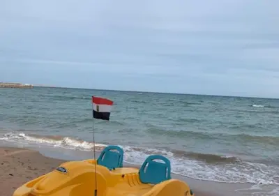 a yellow boat on the beach with a flag at Luxury Cecelia resort in Hurghada
